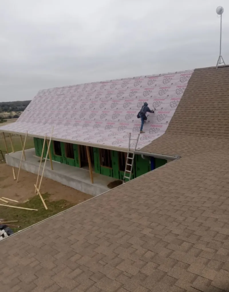 Worker preparing underlayment for a metal roof installation in Beverly